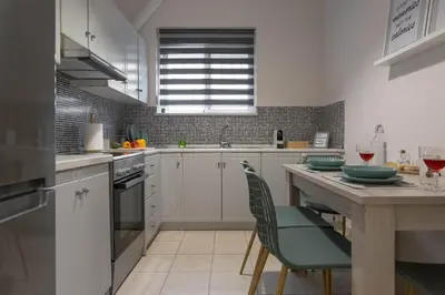 a kitchen with white cabinets and a table with chairs at Blue Haven Chania Apt in Chania Town