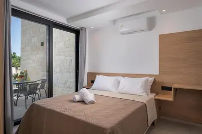 a bedroom with a bed and a balcony with a table at NEA Dreamy Houses in Agia Marina Nea Kydonias