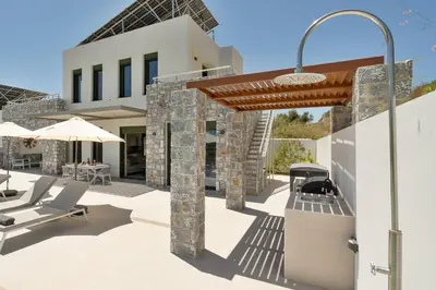 a patio with chairs and umbrellas in front of a house at Villa Meraki in Stalos