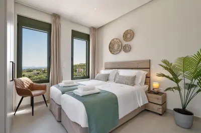 a bedroom with a bed and a chair and windows at Villa Meraki in Stalos