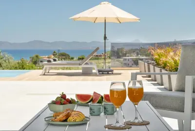 a table with two glasses of wine and fruit at Villa Meraki in Stalos