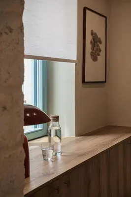 a glass bottle on a wooden table with a window at Off Apartments in Chania Town
