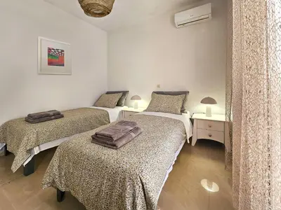 a bedroom with two beds and a table with lamps at Dafne Almyrida Beach Apartment in Almirida