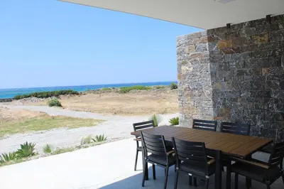 a patio with a table and chairs and the ocean at Astrokastro Frangokastello in Frangokastello