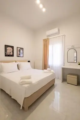a white bedroom with a large bed and a window at Apanemia Apartment in Chania Town