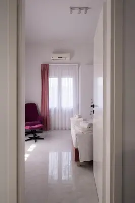 a bathroom with a room with two beds and a chair at Apanemia Apartment in Chania Town