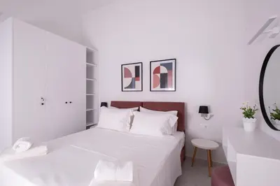 a white bedroom with a bed and a mirror at Apanemia Apartment in Chania Town
