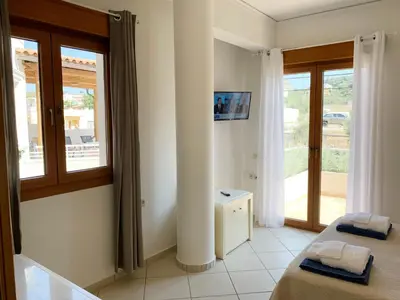 a room with two beds and a balcony with windows at Platanias Memories Studio 3 in Plataniás