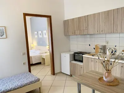 a kitchen with a table and a room with a bed at Platanias Memories Studio 3 in Plataniás