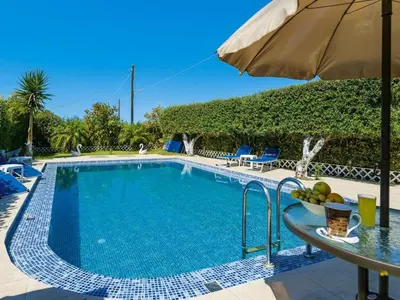 a swimming pool with a table and an umbrella at Holiday home, Marathokefala near Kolimbari in Marathokefála