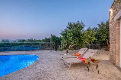 a patio with a chair and a table next to a swimming pool at Villa Alma Libre Kissamos in Kissamos