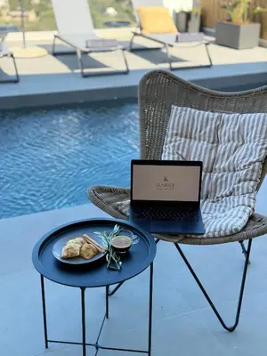 a laptop sitting on a chair next to a plate of food at Sunrise Village Aptera Private Pool Villa in Beritianá