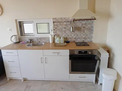 a small kitchen with white cabinets and a sink at andys house in Chania