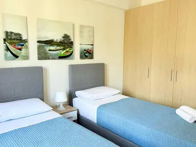 two beds in a room with paintings on the wall at Fifty Shades of Blue 10 sec to sea 5PL 2BD 2BA in Stalos