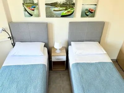 two beds in a room with pictures on the wall at Fifty Shades of Blue 10 sec to sea 5PL 2BD 2BA in Stalos