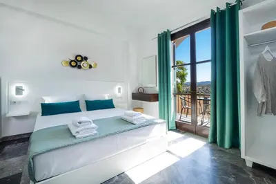 a white bedroom with a bed and a balcony at Anastasia Veridian Living in Kalathas