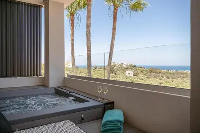a hot tub in a room with a window with palm trees at Kymélia Luxury Residences With Sea View in Galatás