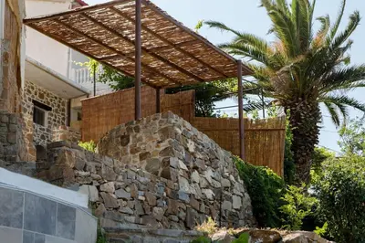 a building with a stone wall and a palm tree at Cozy House Zoi -Top Views, On The Way To Elafonisi in Élos