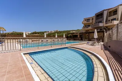 a large swimming pool in a resort with a building at Sunrise Suites & Apartments in Kalyves