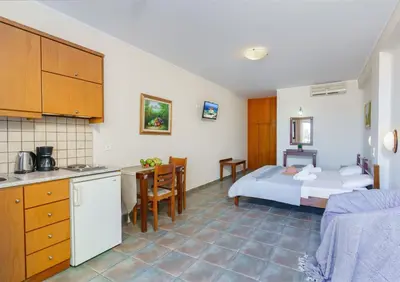 a kitchen and a bedroom with a bed and a table at Sunrise Suites & Apartments in Kalyves