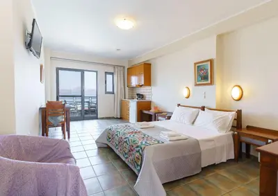 a bedroom with a bed and a table and a kitchen at Sunrise Suites & Apartments in Kalyves