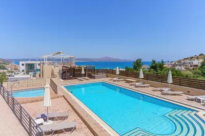 a pool with chairs and umbrellas on a building at Sunrise Suites & Apartments in Kalyves
