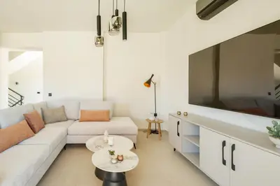 a living room with a white couch and a large tv at Madre Tierra Boutique Villas 1 & 2 in Liyidhés