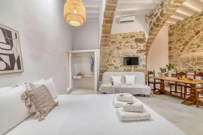 a living room with a white bed and a table at The Mulberry Stonehouse Mountain - Sea View in Kalleryianá