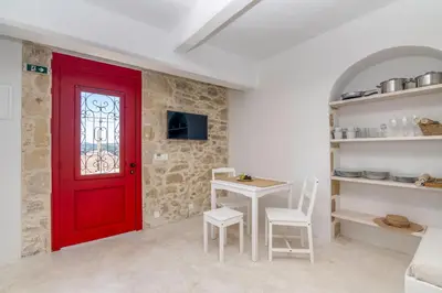 a red door in a room with a table and chairs at The Mulberry Stonehouse Mountain - Sea View in Kalleryianá