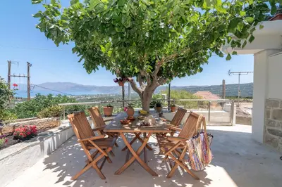 a wooden table and chairs on a patio with a tree at The Mulberry Stonehouse Mountain - Sea View in Kalleryianá