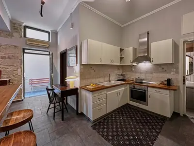a kitchen with white cabinets and a table and chairs at Spiti an urban heaven in Chania Town