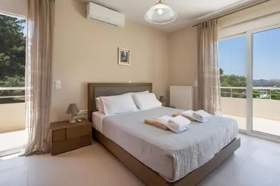 a bedroom with a bed and a large window at Kyparisses Villa with Private Pool in Chania Town