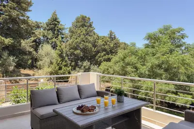 a patio with a table and a couch on a balcony at Kyparisses Villa with Private Pool in Chania Town