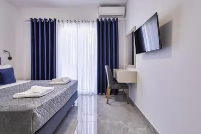 a room with two beds and a desk and a television at Jimmis Apartment in Chania Town