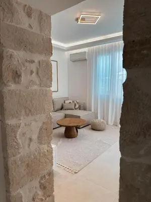 a living room with a stone wall and a table at Dida stone home in Chania Town