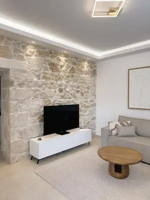 a living room with a tv on a stone wall at Dida stone home in Chania Town
