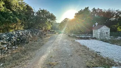 a dirt road next to a stone wall and a building at The Root House - Crete Stay in Vafés