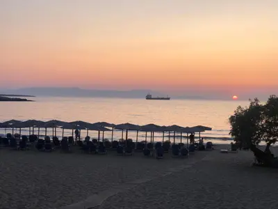 a beach with chairs and umbrellas at sunset at Casa del Sol - Kalathas in Kalathas