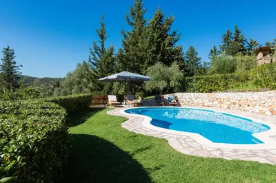 a swimming pool in a yard with an umbrella at Vrisali Traditional Stone Villa in Gerolakkos