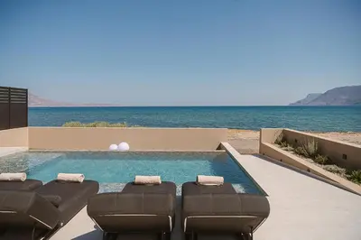a swimming pool with lounge chairs and the ocean at Onora Villa - Steps from the Sea by etouri in Nopíyia
