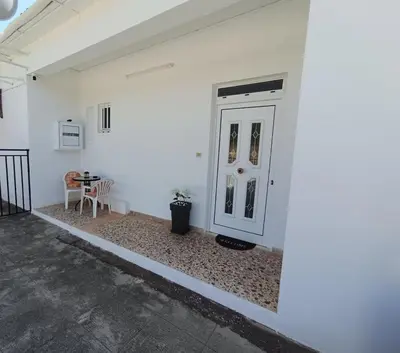 a white wall with a door and a table at Veranda with endless view in Fournés