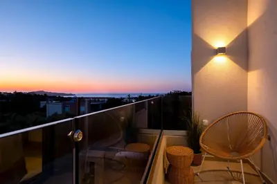 a balcony with a view of a city at sunset at Aladdin Luxury Suites With Shared Pool in Galatás