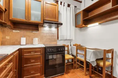 a kitchen with wooden cabinets and a black stove at Spitatsi - Home with Yard in Chania Town