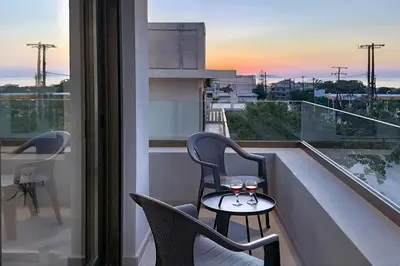 a balcony with two chairs and a table with wine glasses at Lum Urban Suites in Chania Town