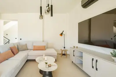 a living room with a white couch and a large tv at Madre Tierra Boutique Villa 3 in Potistíria
