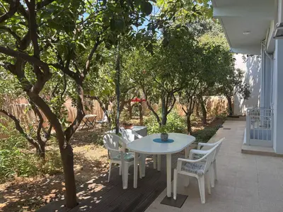 a white table and chairs on a patio with trees at Orange Tree in Chania Town