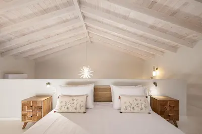 a bedroom with a large white bed with wooden ceilings at Villa Manmar 2BR with Sleeping Lofts by etouri in Spiliá