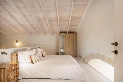 a bedroom with a large bed with a wooden ceiling at Villa Manmar 2BR with Sleeping Lofts by etouri in Spiliá