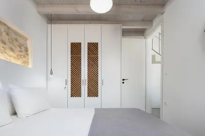 a bedroom with white walls and a bed and a door at Villa Manmar 2BR with Sleeping Lofts by etouri in Spiliá