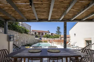 a patio with a table and chairs and a swimming pool at Villa Manmar 2BR with Sleeping Lofts by etouri in Spiliá